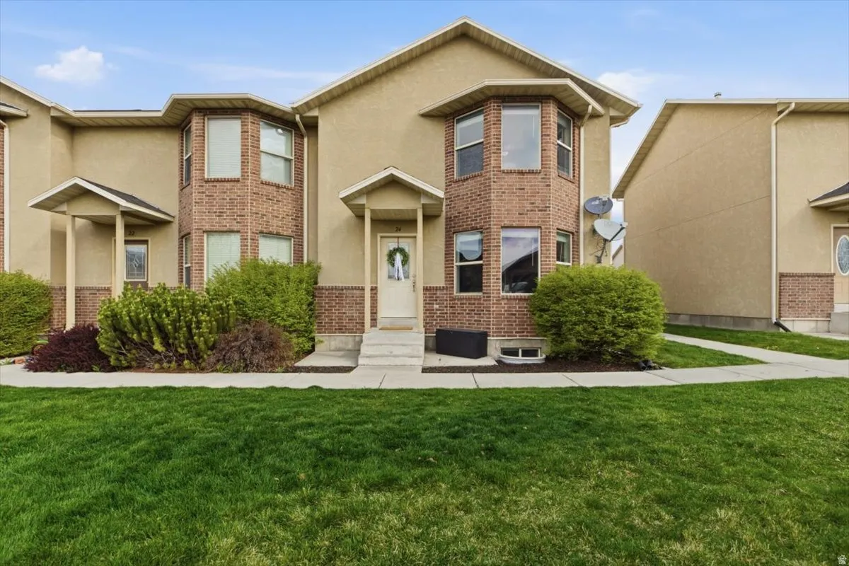 Traditional-style house featuring brick siding, a front yard, and stucco siding