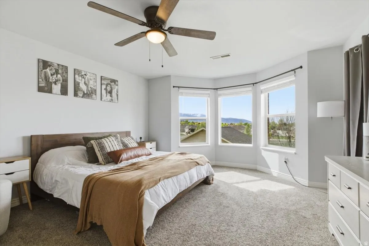 Carpeted bedroom with ceiling fan and a mountain view