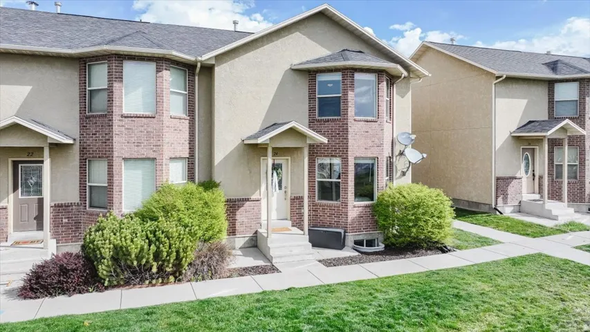 Traditional-style house with stucco siding, brick siding, a front lawn, and entry steps