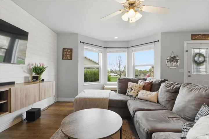 Living room featuring ceiling fan, dark wood finished floors, recessed lighting, and wooden walls