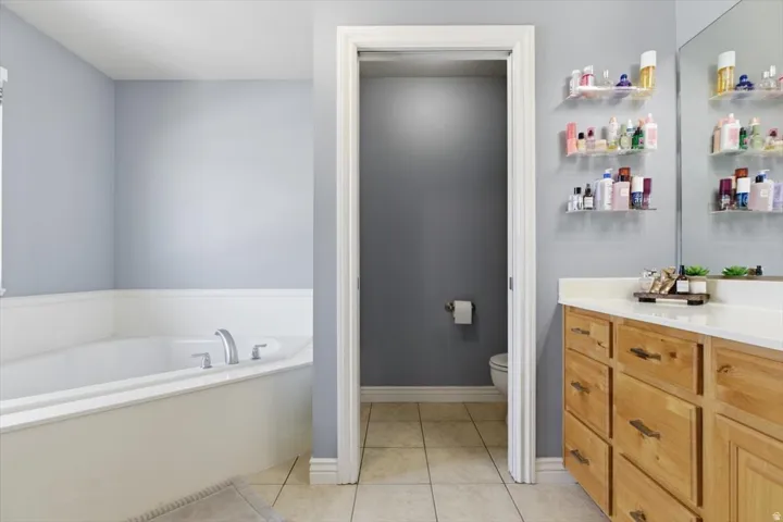 Bathroom with vanity, a garden tub, and light tile patterned floors