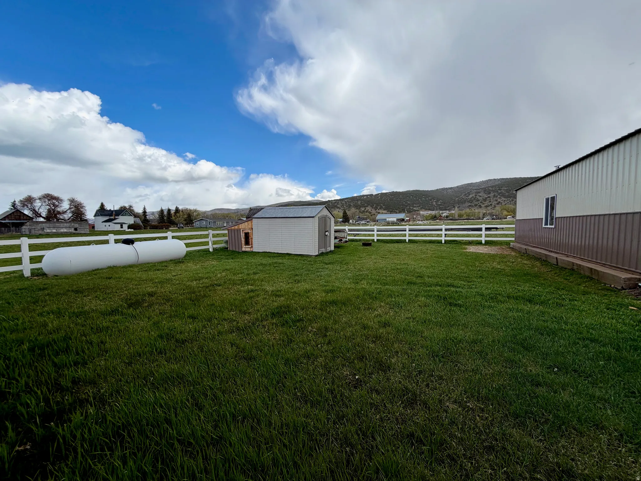 Fenced backyard with a storage unit and a mountain view