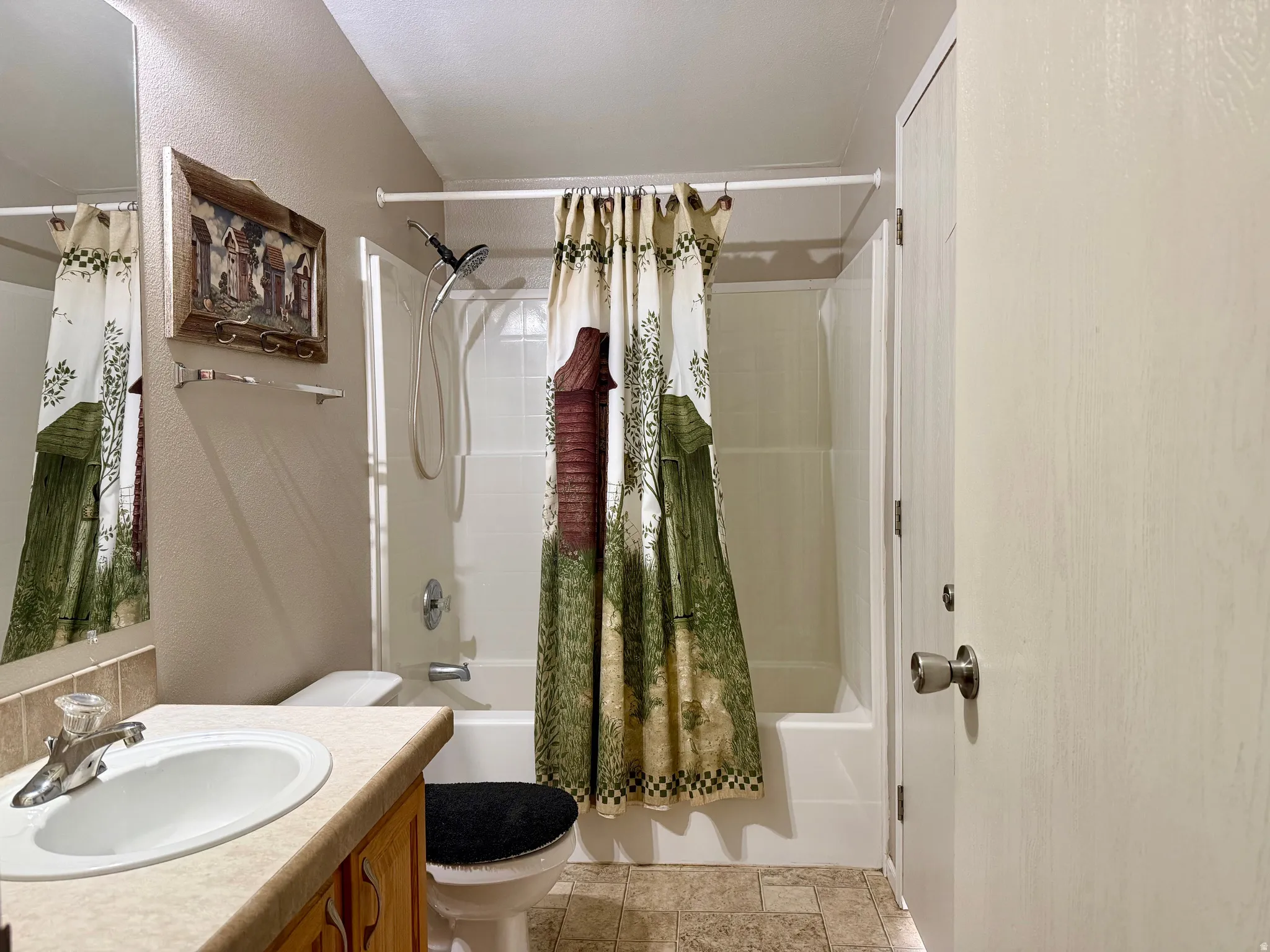 Bathroom featuring vanity, shower / tub combo with curtain, and a textured wall