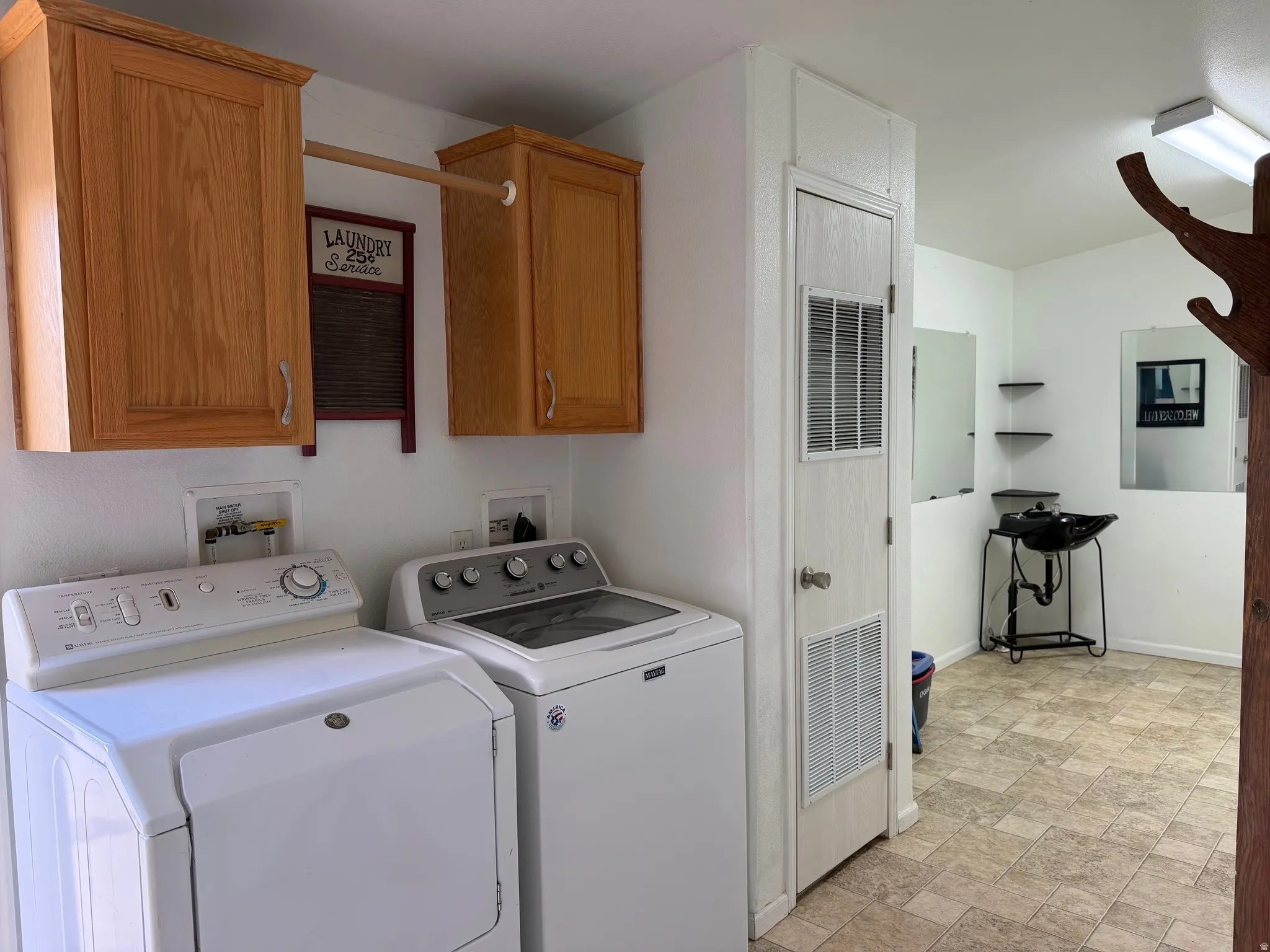 Laundry room with stone finish flooring, a heating unit, separate washer and dryer, and cabinet space