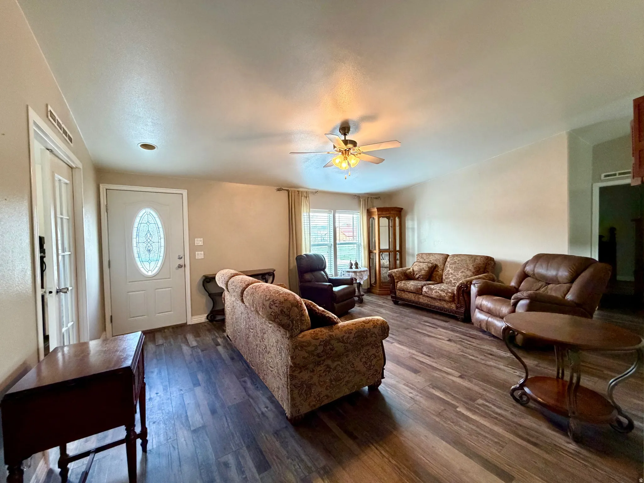 Living area featuring dark wood finished floors and a ceiling fan