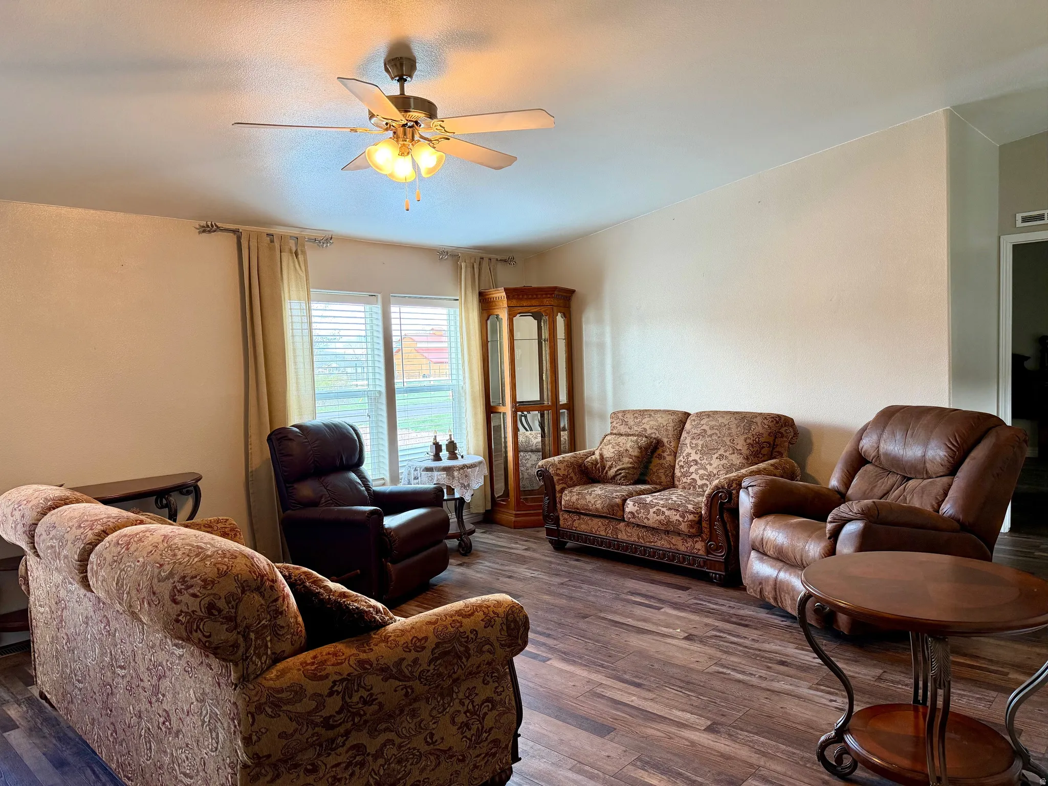 Living room featuring dark wood-style floors and a ceiling fan