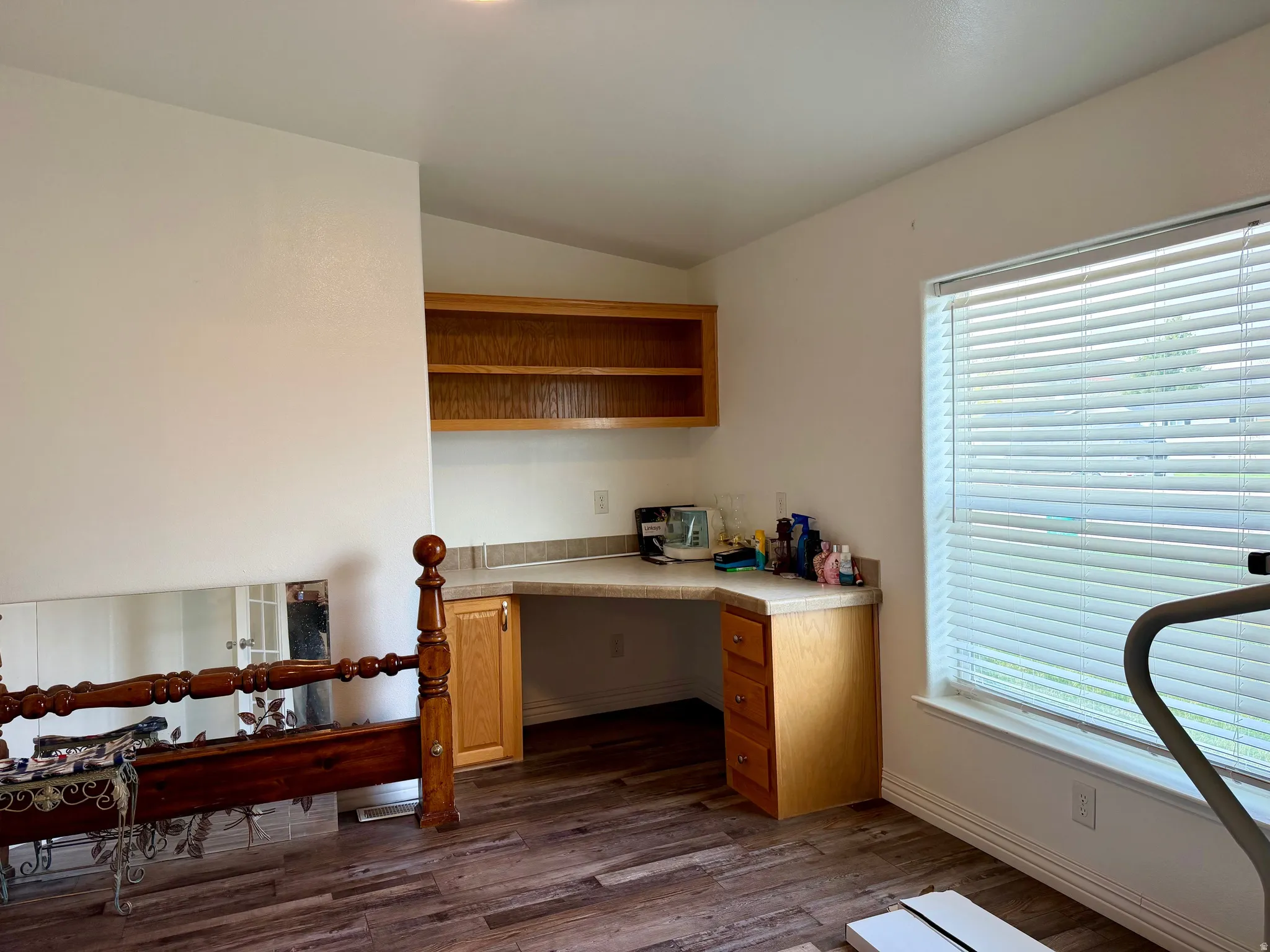 Office space with dark wood finished floors, built in desk, and vaulted ceiling