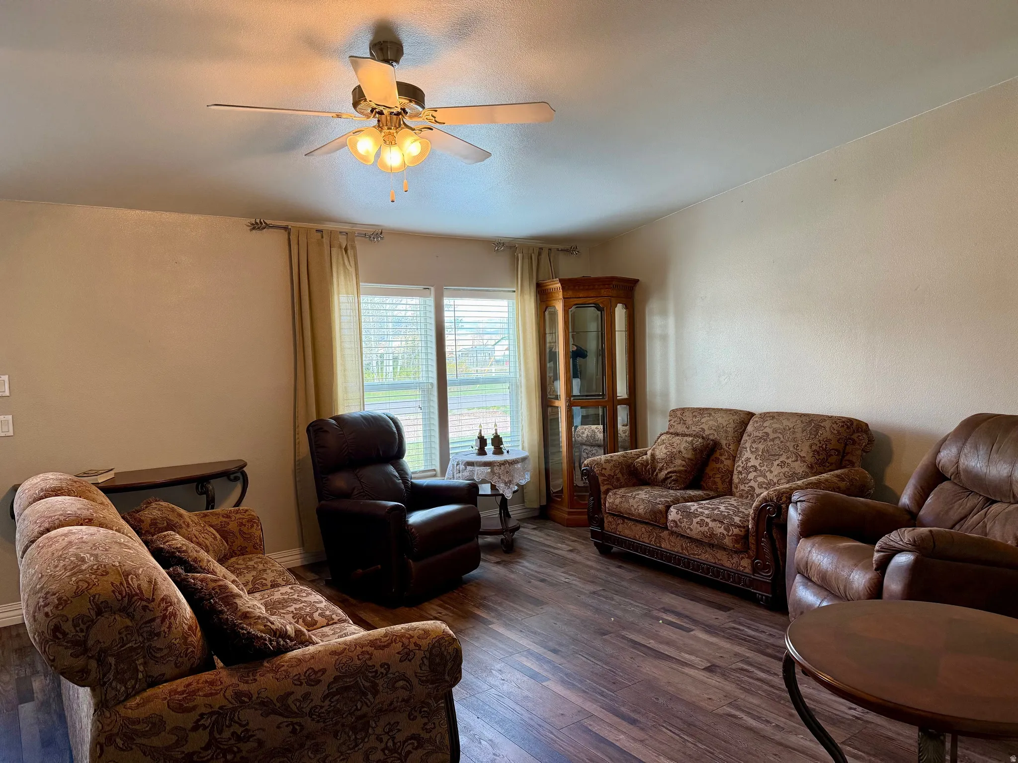 Living area featuring dark wood-type flooring and a ceiling fan