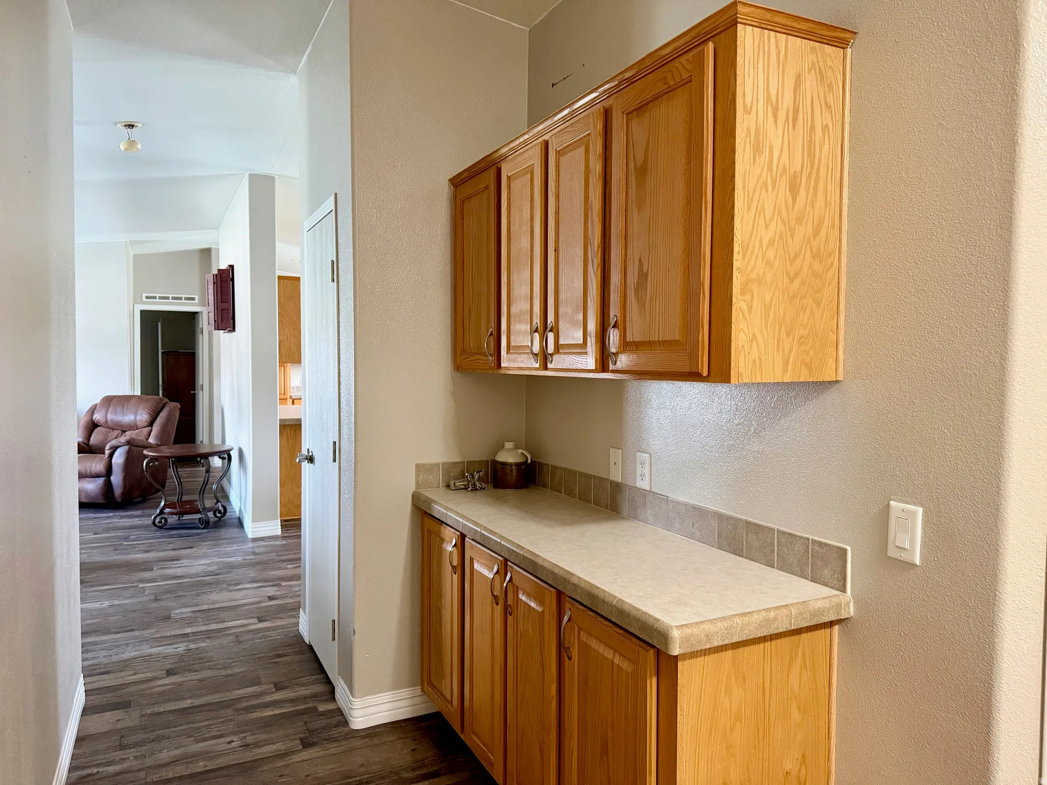 Kitchen featuring light countertops, dark wood-style floors, a textured wall, and wood finish cabinets