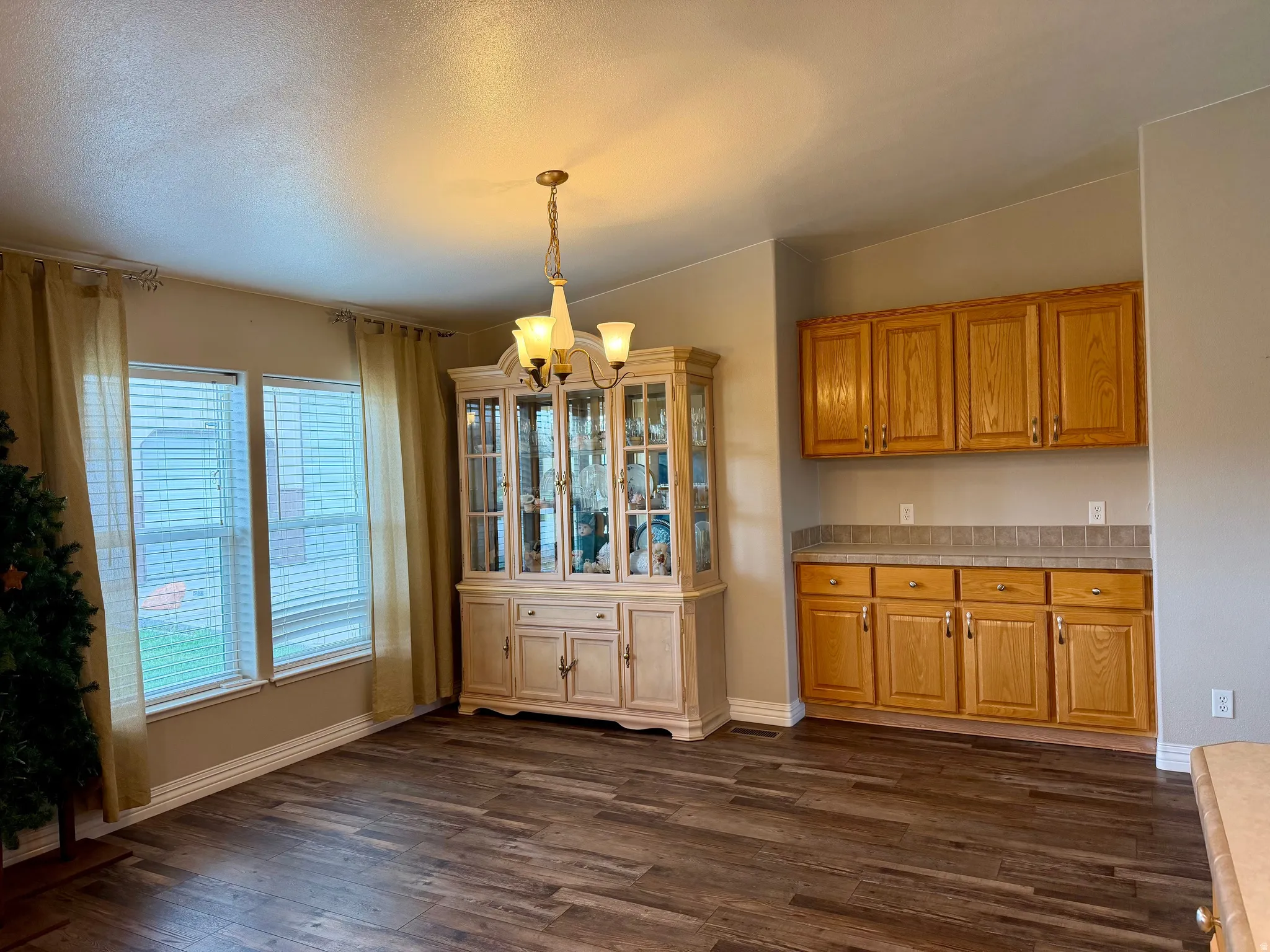 Unfurnished dining area featuring hanging lights, dark wood-style flooring, and a textured ceiling