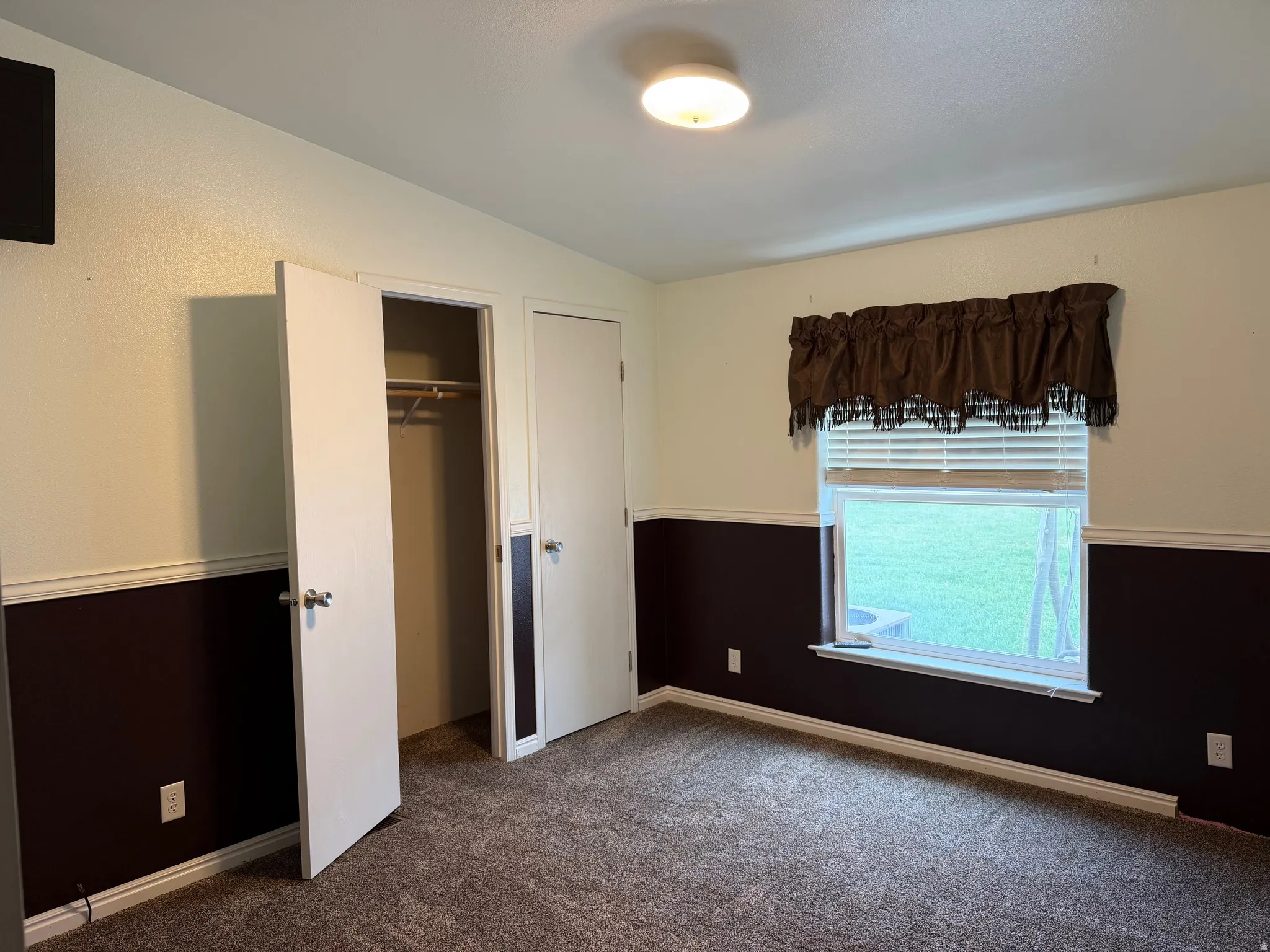 Unfurnished bedroom featuring dark colored carpet, a closet, and vaulted ceiling