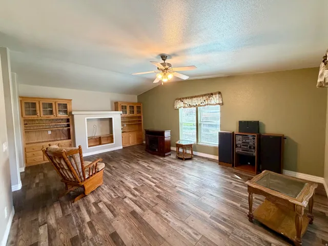 Living area with dark wood-type flooring and a ceiling fan