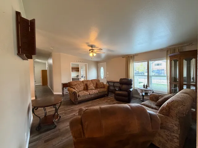 Living room featuring ceiling fan, dark wood finished floors, and lofted ceiling