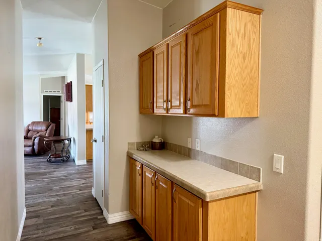Kitchen featuring light countertops, dark wood-style floors, a textured wall, and wood finish cabinets