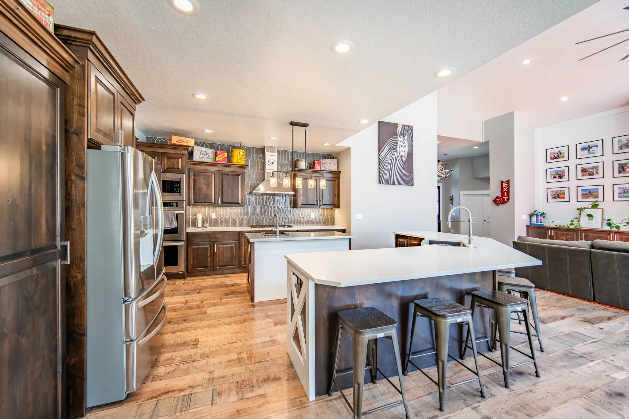 Kitchen with stainless steel appliances, a kitchen breakfast bar, prep island, open floor plan, wood-type flooring, and light stone countertops