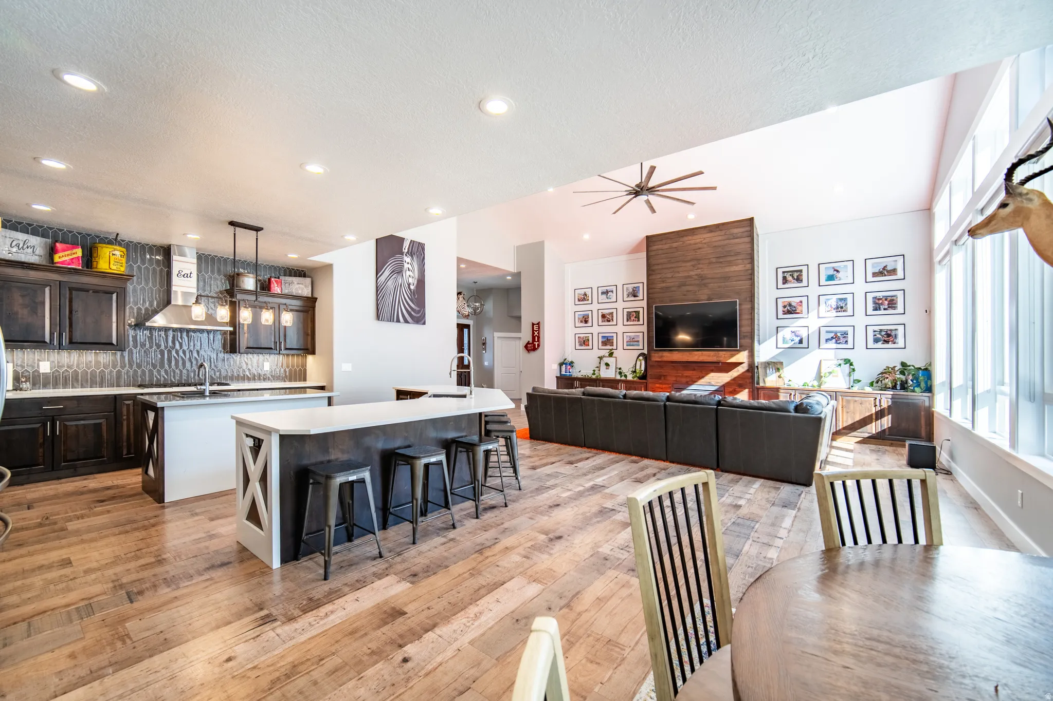 Kitchen featuring open floor plan, dark wood finish cabinetry, backsplash, a kitchen breakfast bar, prep island and wood finished floors
