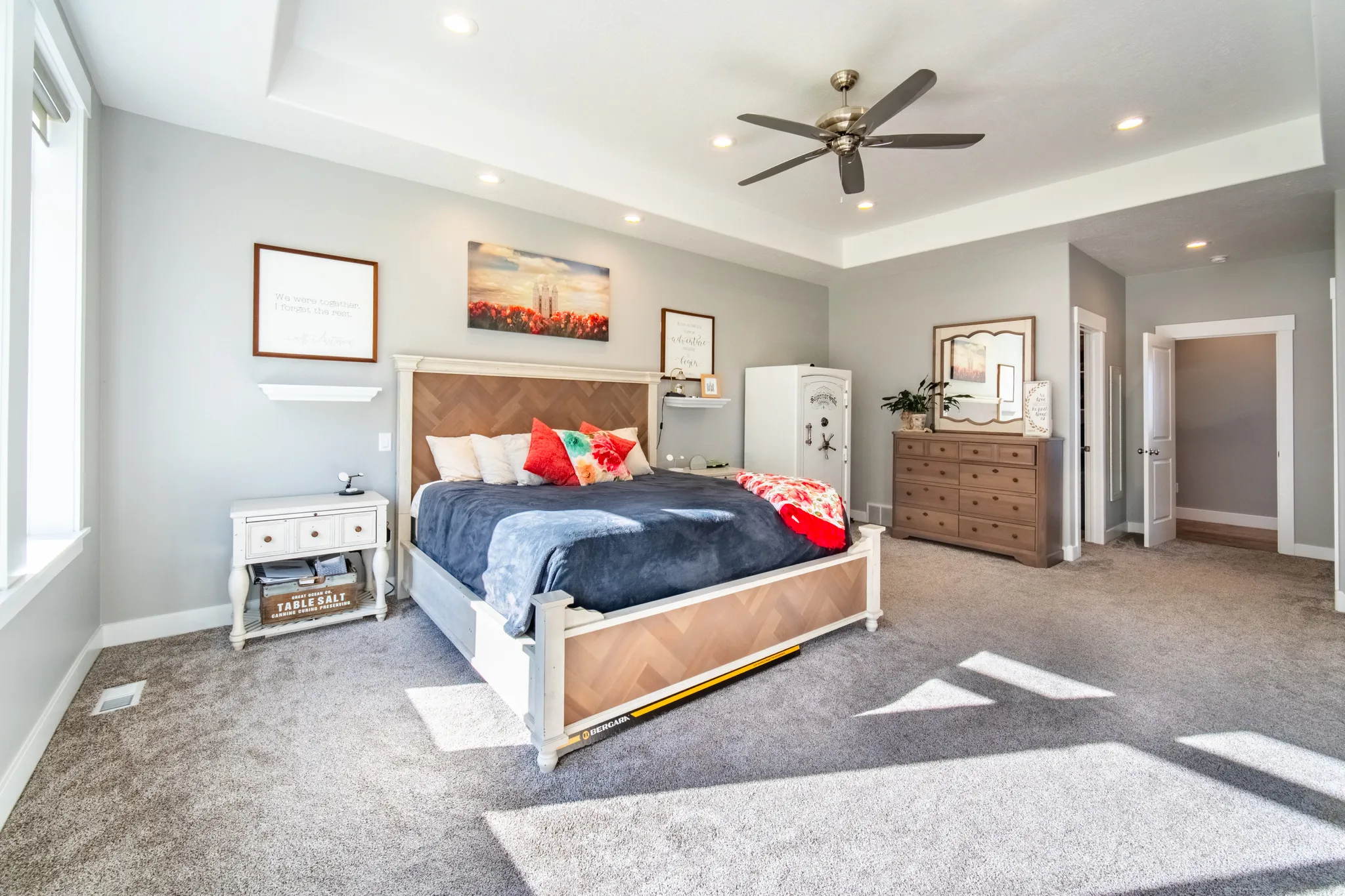 Primary bedroom with light colored carpet, ceiling fan, recessed lighting, and a tray ceiling