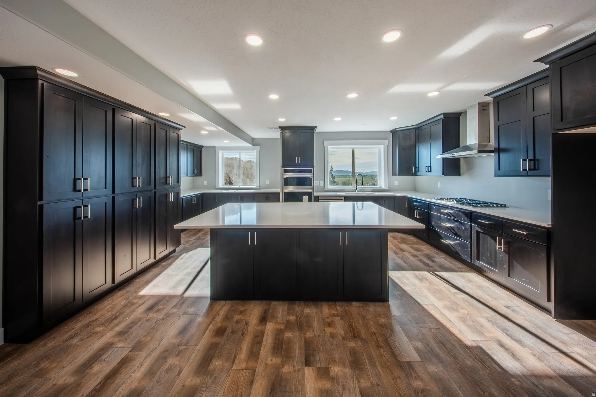 Kitchen featuring a kitchen island, wood-style floors, recessed lighting, stainless steel appliances, and light stone counters