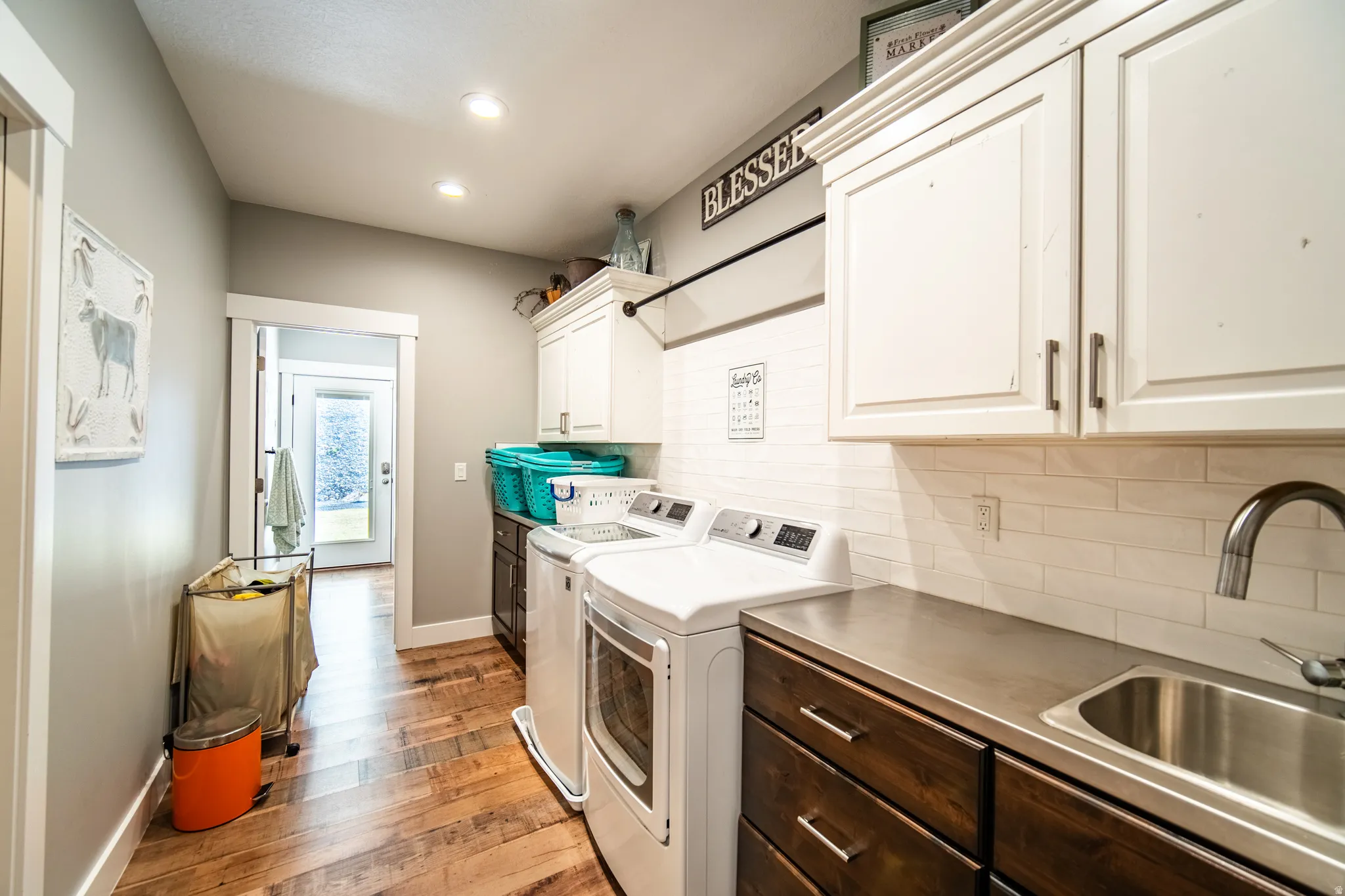 Laundry room featuring washer and dryer, cabinet space, wood-style flooring, and recessed lighting