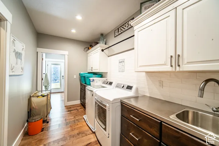 Laundry room featuring washer and dryer, cabinet space, wood-style flooring, and recessed lighting