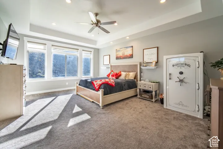 Primary bedroom featuring a tray ceiling, ceiling fan, and recessed lighting