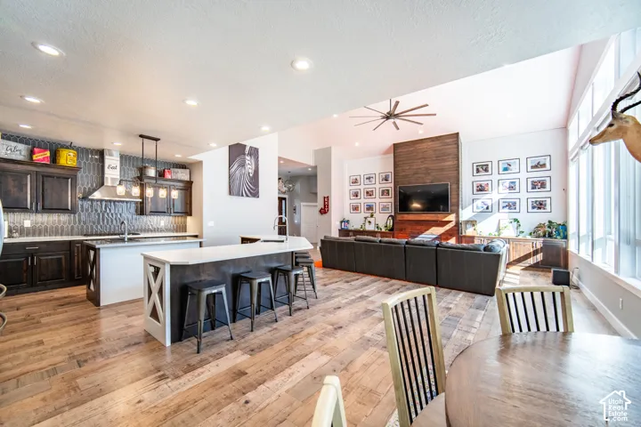 Kitchen featuring open floor plan, dark wood finish cabinetry, backsplash, a kitchen breakfast bar, prep island and wood finished floors