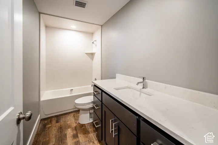 Full bathroom with vanity, wood-type flooring, bathing tub / shower combination, and recessed lighting