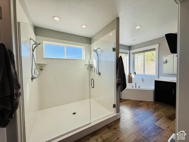 Glass-enclosed shower with multiple showerheads, recessed lighting, and a transom window