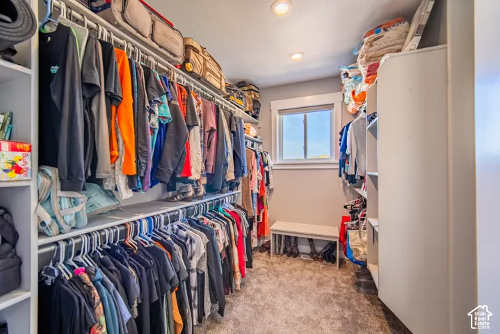 One of two primary bedroom walk in closet with colored carpet