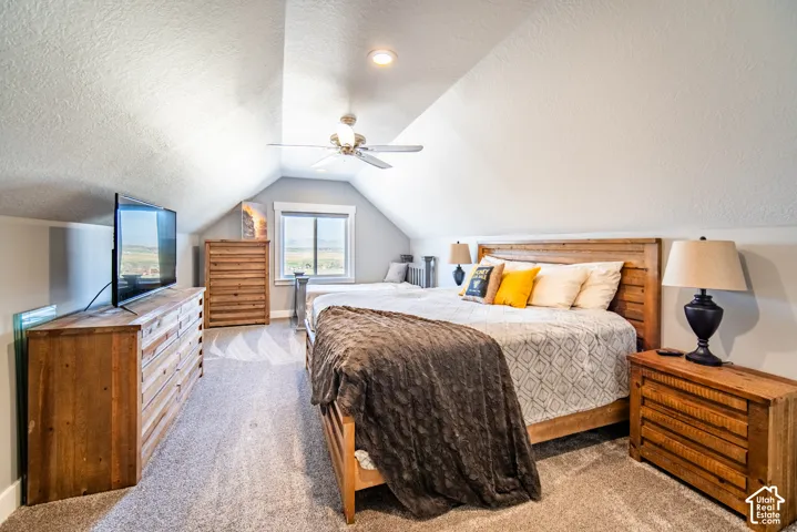 Bedroom featuring a textured ceiling, light carpet, and a ceiling fan