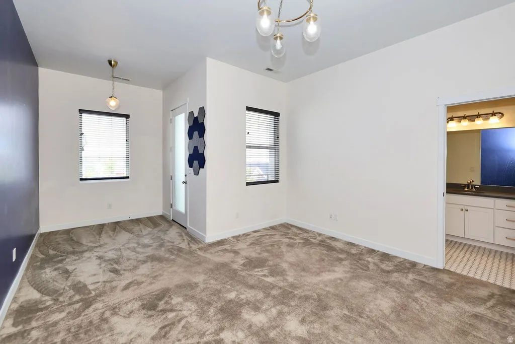 Unfurnished dining area with light colored carpet and a chandelier