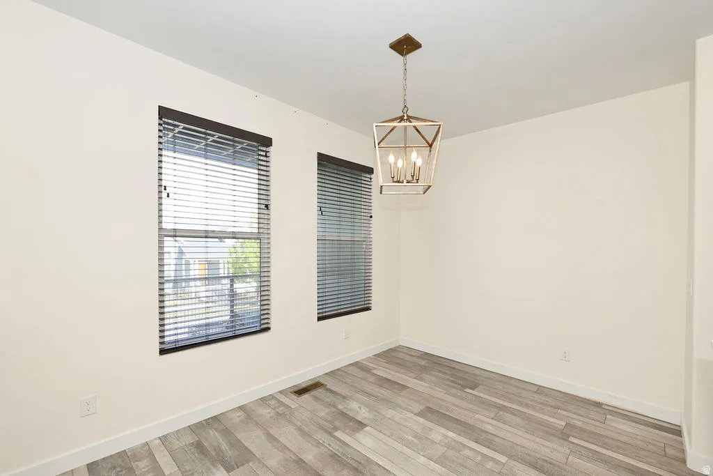 Spare room with suspended lighting and light wood finished floors