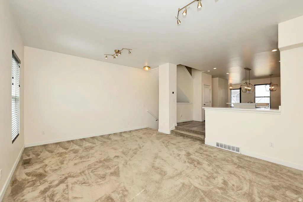 Unfurnished living room featuring light carpet and track lighting