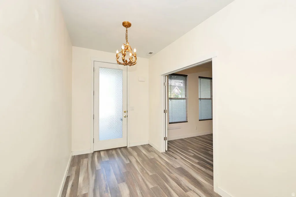 Unfurnished dining area with a chandelier and wood finished floors