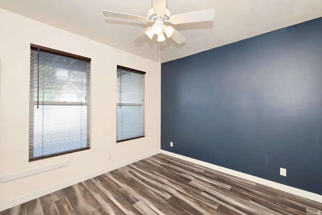 Unfurnished room featuring dark wood-type flooring and a ceiling fan