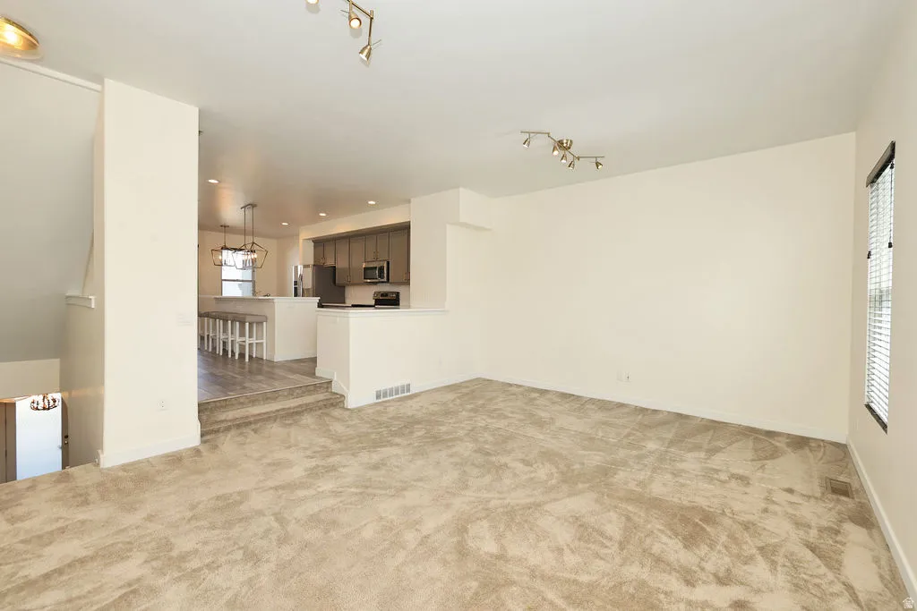 Unfurnished living room with light carpet and track lighting