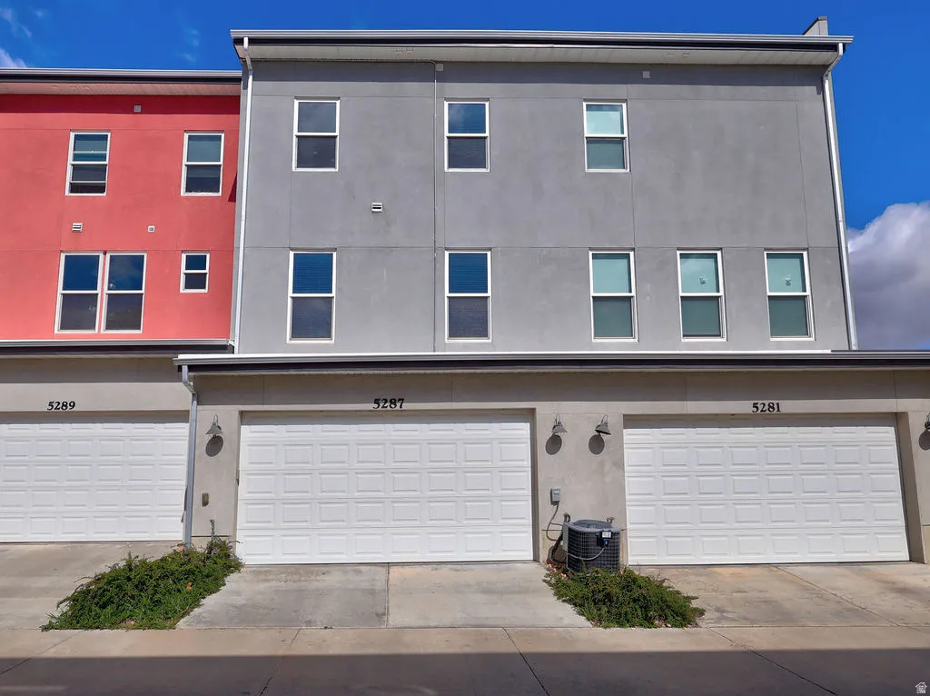 View of front facade featuring an attached garage, stucco siding, and driveway