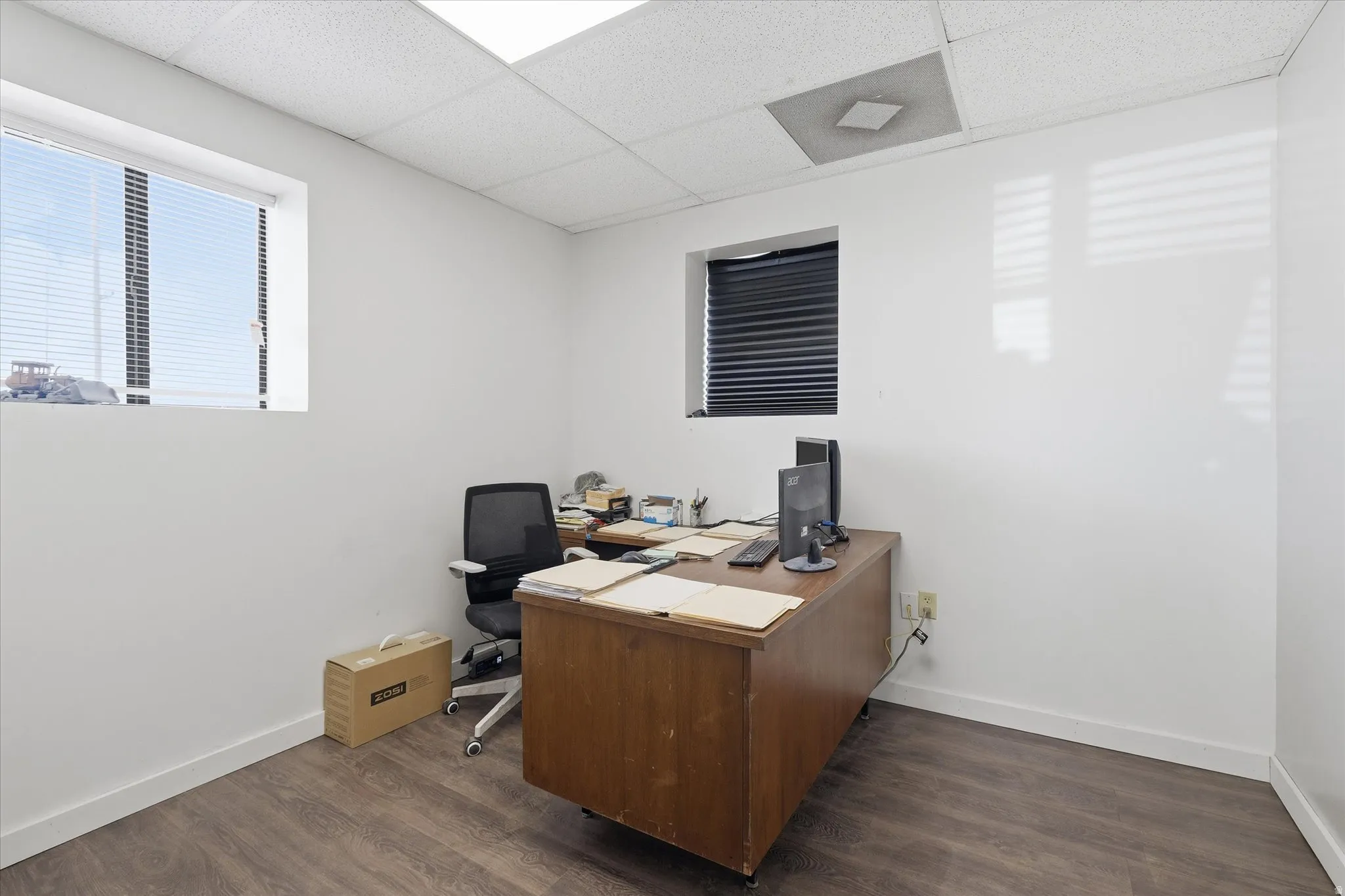 Office area with a paneled ceiling and dark wood finished floors