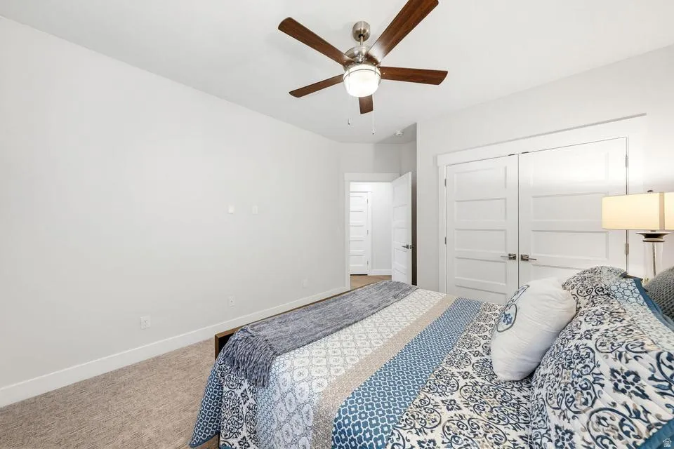 Carpeted bedroom featuring a ceiling fan and a closet