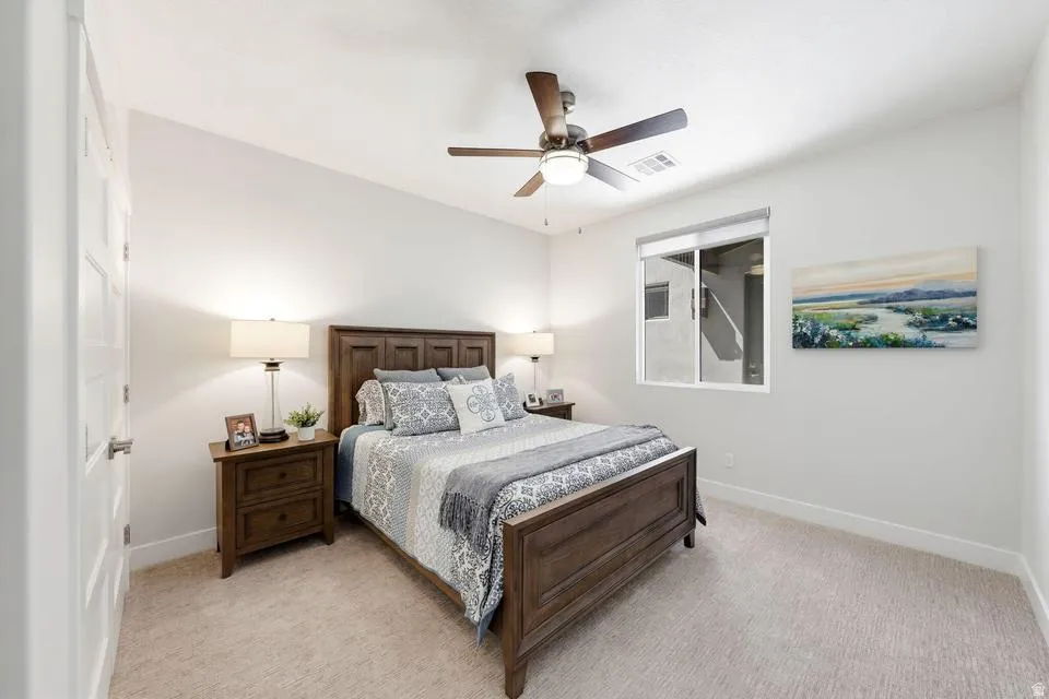 Bedroom with light colored carpet and a ceiling fan