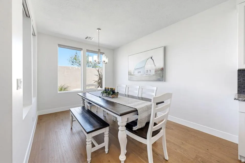 Dining area featuring light wood-style floors, a chandelier, and a textured ceiling
