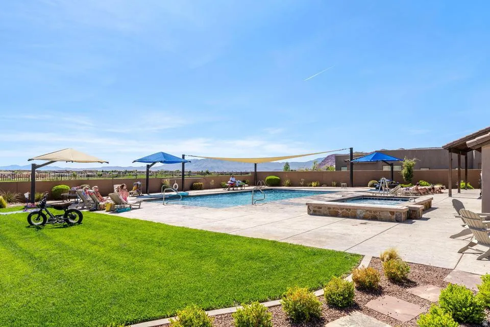 View of swimming pool with patio surround, a fenced backyard, a mountain view, and an in-ground hot tub