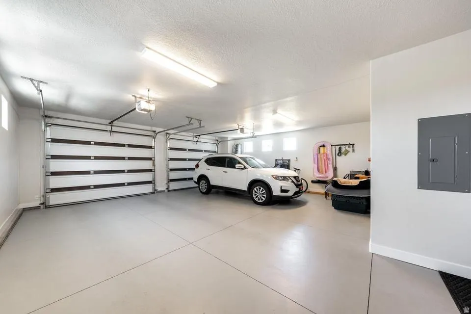 Garage featuring electric panel and baseboards