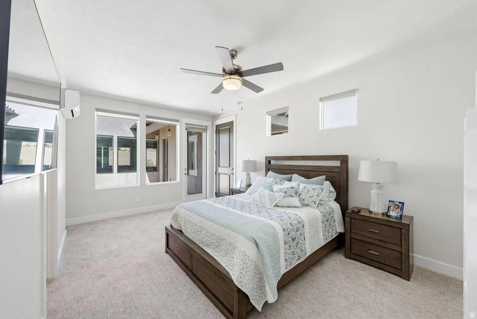 Bedroom featuring light colored carpet, ceiling fan, and multiple windows
