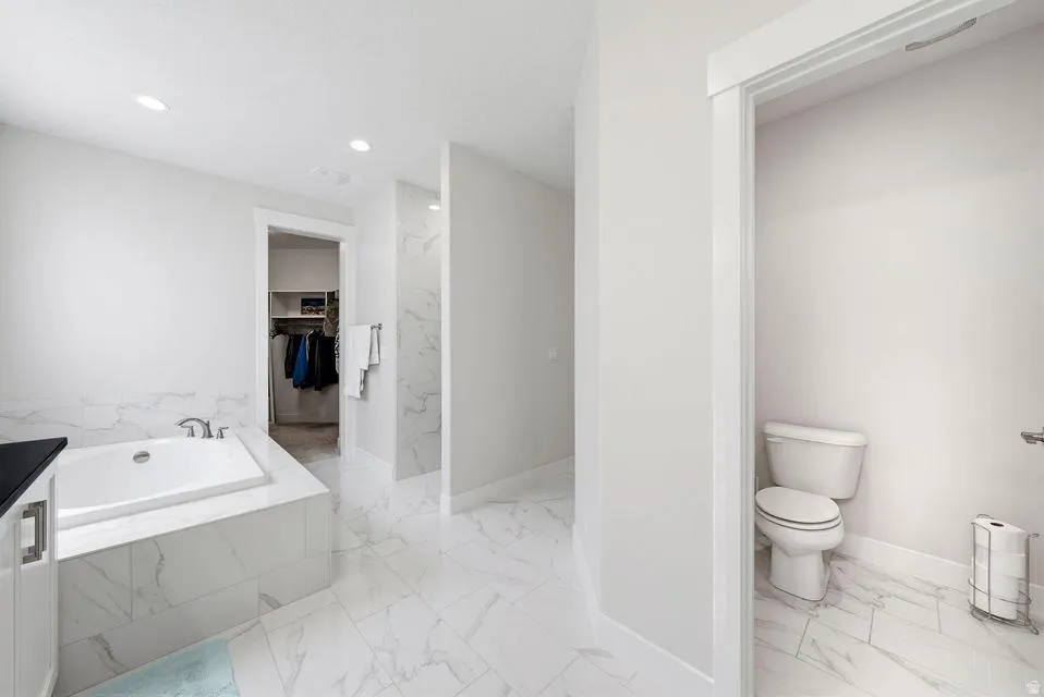 Full bathroom with a walk in closet, a garden tub, light marble finish flooring, recessed lighting, and a marble finish shower