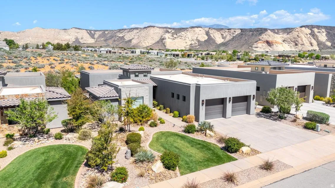 View of front of house with a mountain view, driveway, a garage, stucco siding, and a front yard