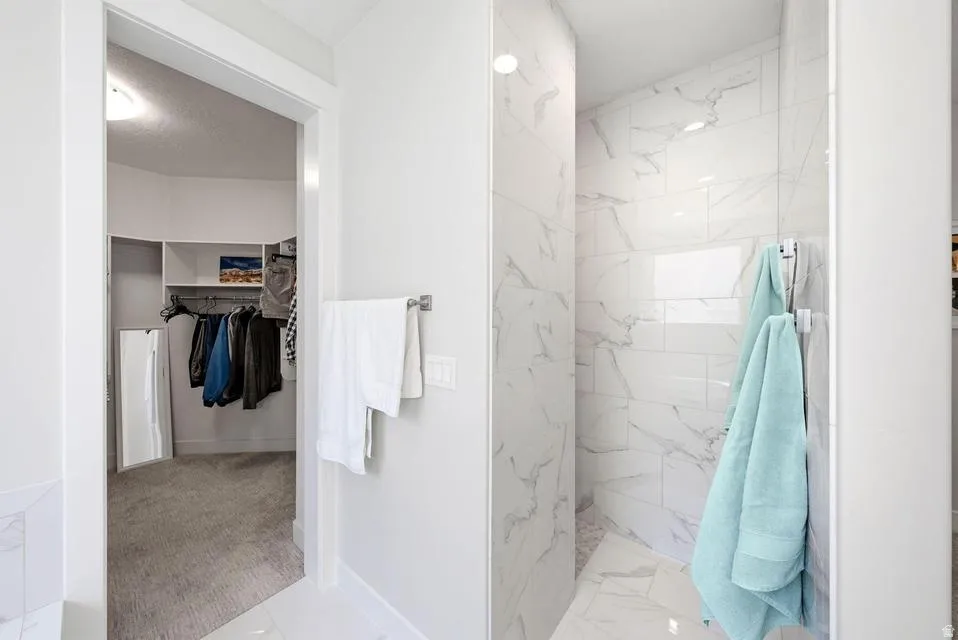 Full bathroom with a walk in closet, a marble finish shower, and light marble finish floors