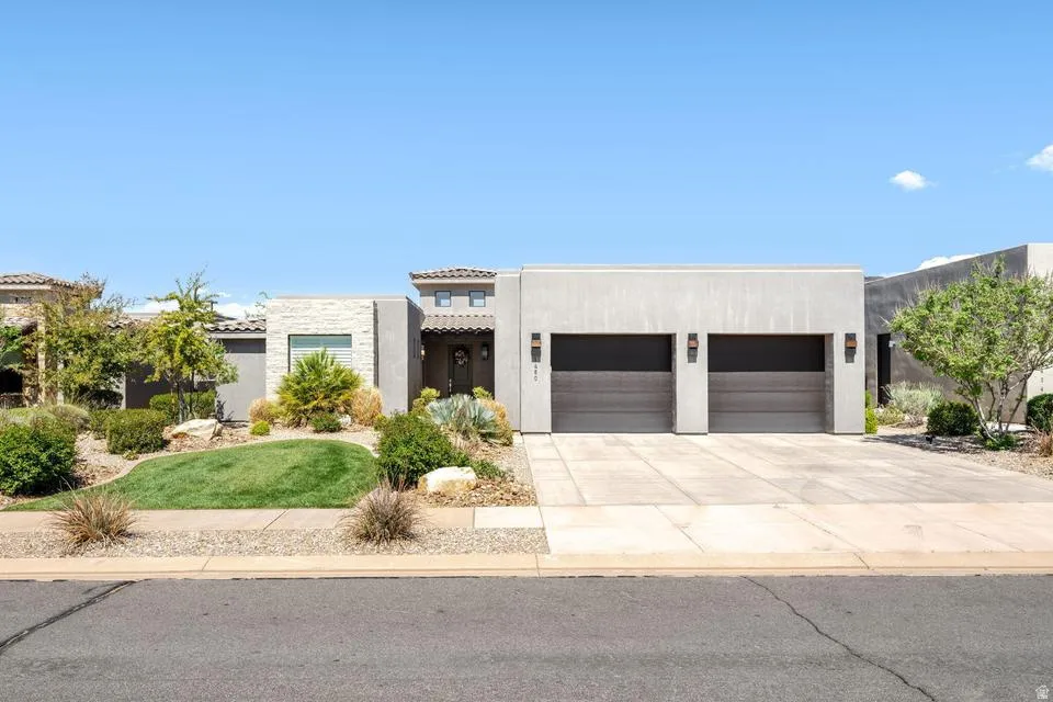 View of front facade with an attached garage, driveway, and stucco siding