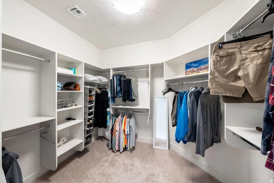 Walk in closet featuring light colored carpet