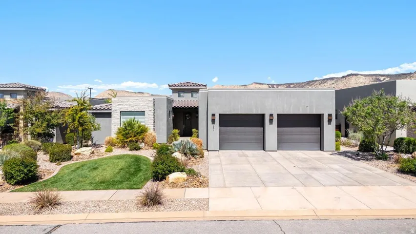 View of front of home with an attached garage, concrete driveway, and stucco siding